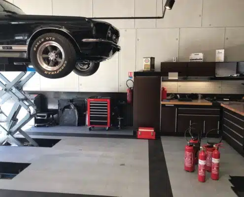 Extincteurs rouges installés dans un garage automobile équipé d'un pont élévateur