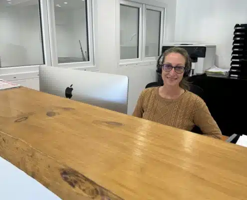 Fanny, souriante avec casque audio, accueille les clients à la réception de l'entreprise de sécurité incendie