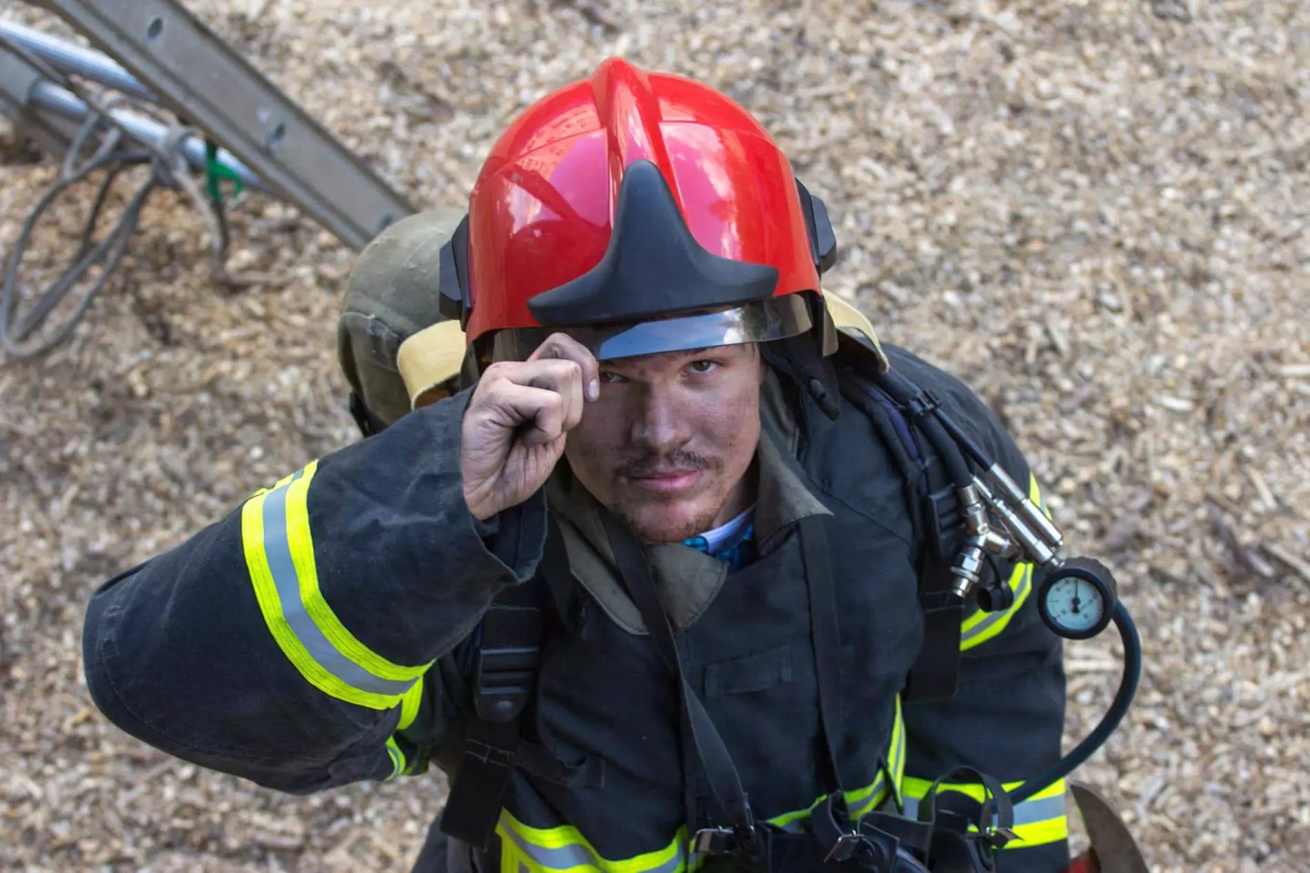 Pompier casqué en équipement de sécurité incendie ajustant son casque rouge