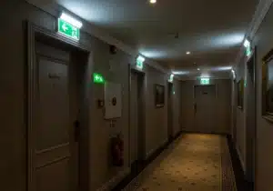 Couloir d'hôtel avec blocs autonomes d'éclairage de sécurité BAES et extincteur mural