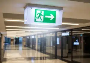 Bloc autonome d'éclairage de sécurité BAES lumineux signalant une sortie de secours dans un couloir