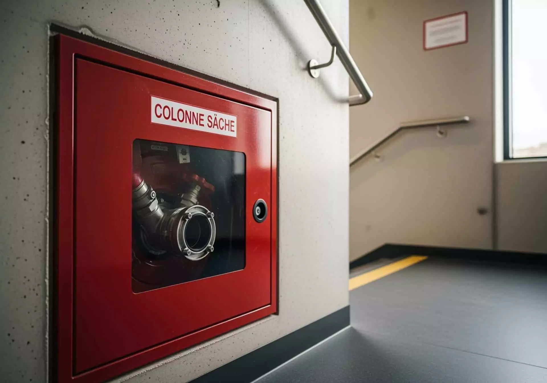 Coffret rouge de colonne sèche avec raccord pompier dans une cage d'escalier