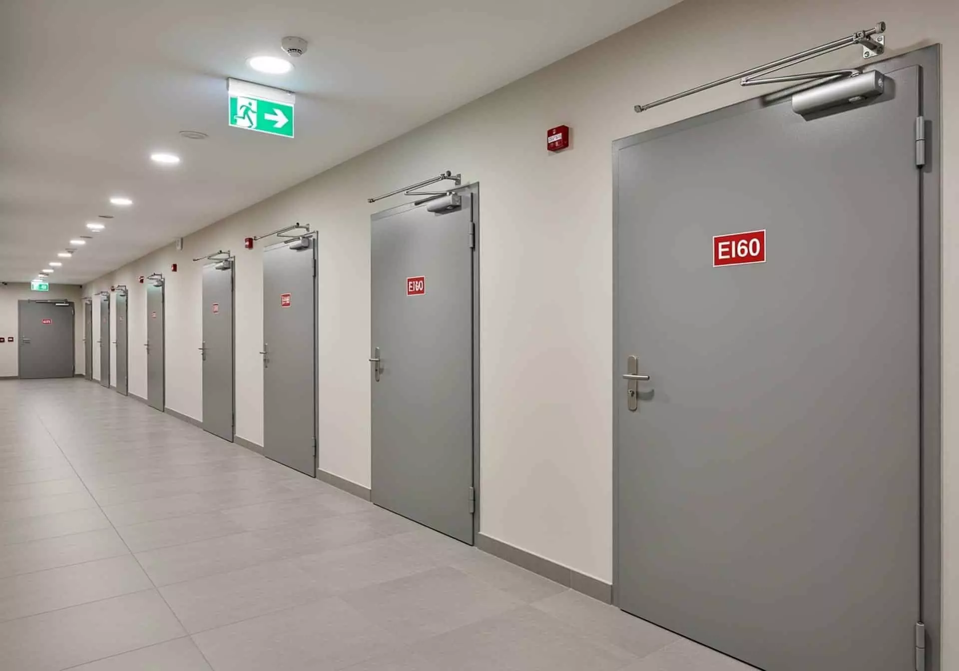 Couloir avec portes coupe-feu EI60 grises equipees de ferme-portes et signalisation issue de secours