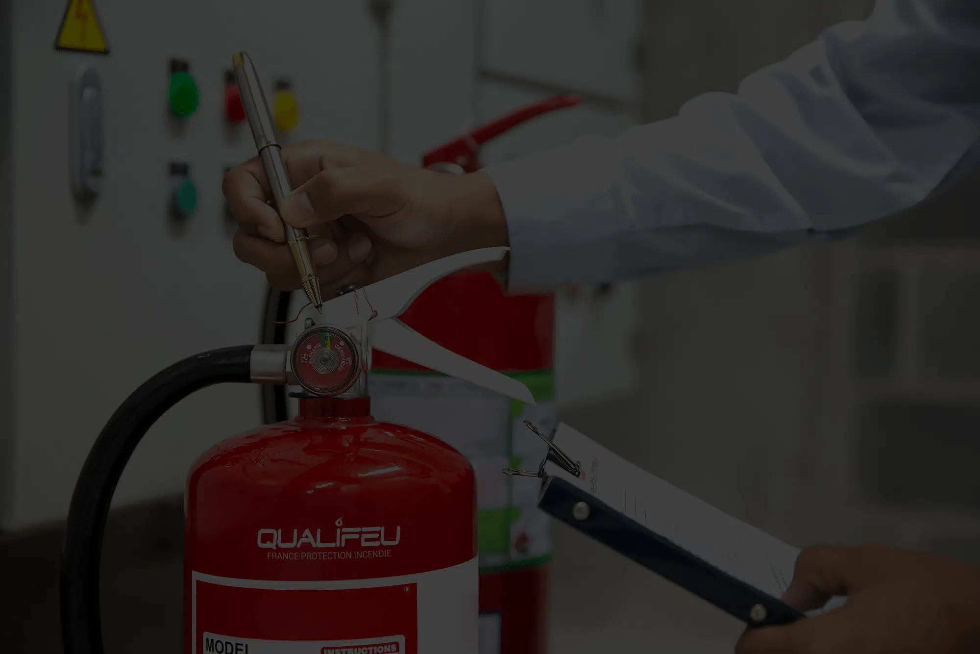 Technicien vérifiant le manomètre d'un extincteur rouge Qualifeu lors d'une inspection de sécurité incendie