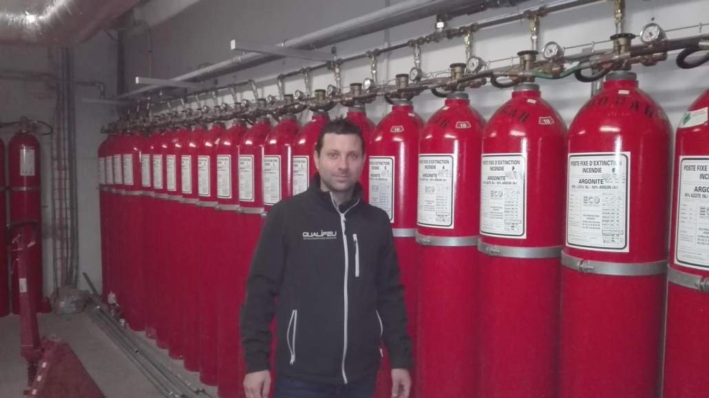 Technicien Qualifeu devant une rangée de bouteilles d'extinction incendie Argonite à Bordeaux