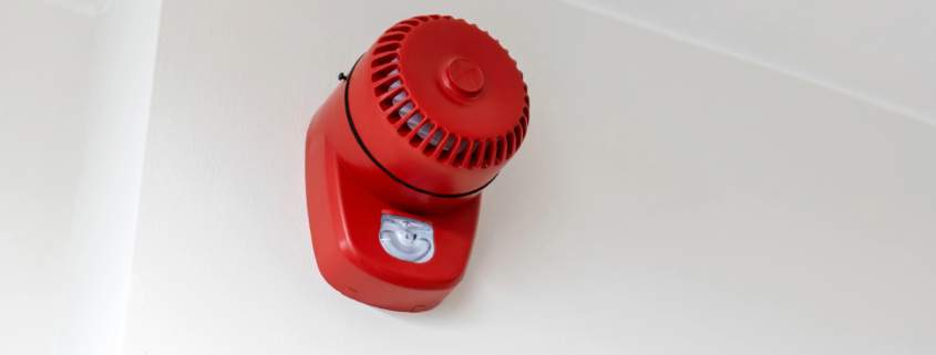 Sirène rouge d'alarme incendie fixée au plafond dans un ERP