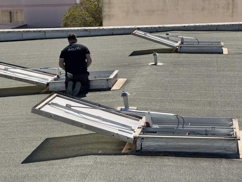 désenfumage Qualifeu Technicien Qualifeu inspectant des exutoires de désenfumage sur une toiture-terrasse