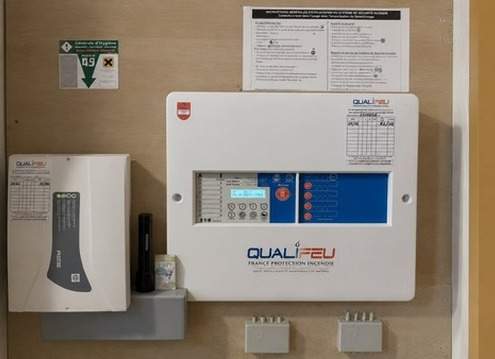 Centrale d'alarme incendie Qualifeu murale avec panneau de contrôle et notice de sécurité