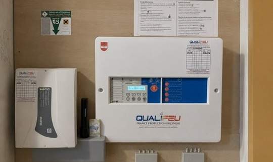 Centrale d'alarme incendie Qualifeu murale avec panneau de contrôle et notice de sécurité