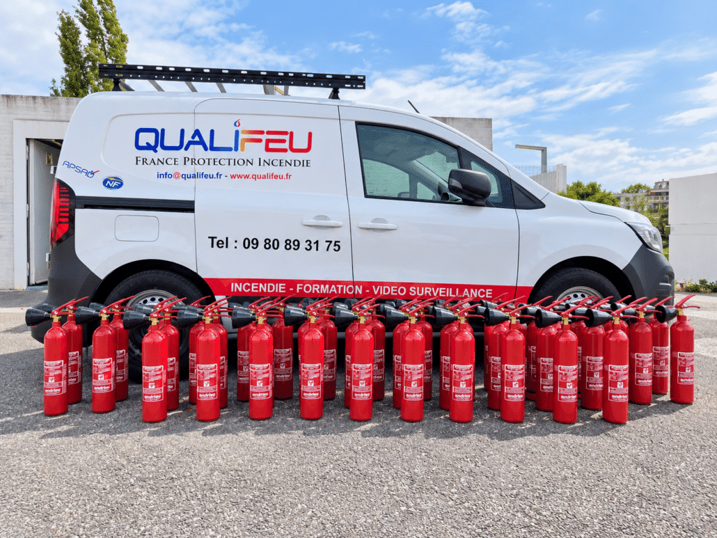 Rangée d'extincteurs rouges alignés devant un véhicule utilitaire Qualifeu protection incendie